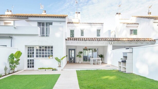 Un edificio residenziale moderno con un patio, un'area pranzo e un prato curato.