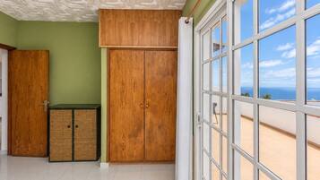 Una habitación con un ventanal grande, un armario de madera y una puerta.