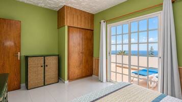 Una habitación con un gran ventanal corredizo que da a un balcón con vista a la piscina.