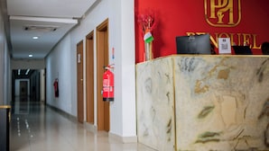 Un mostrador de recepción de hotel con una pared roja, un extintor y un cartel con el nombre del hotel.