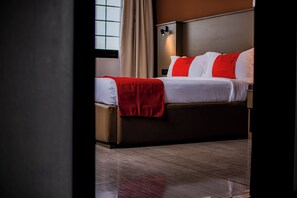 Una habitación de hotel con cama, mesita de noche y ventana con cortinas.