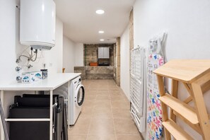 Zona de lavandería con lavadora, tendedero y refrigerador con dibujos infantiles.