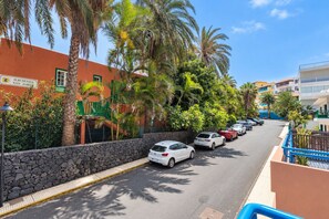 Calle flanqueada por autos estacionados, palmeras y edificios, con un letrero que dice 'Hacienda San Jose'.
