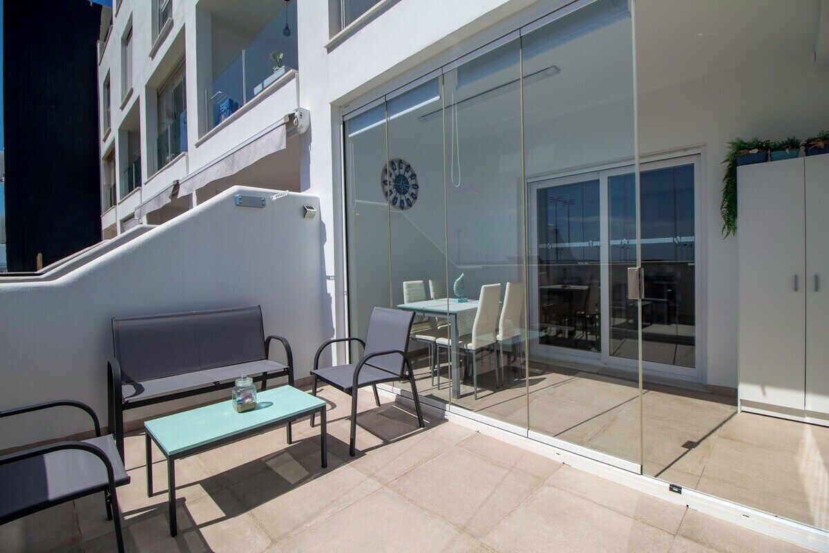 A balcony with a glass door, a clock, and outdoor furniture.