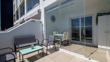 A balcony with a glass door, a clock, and outdoor furniture.