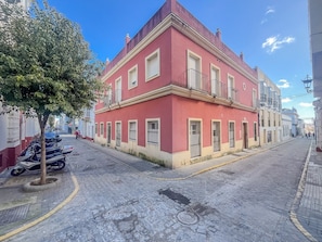Ein rotes Gebäude mit einem Balkon, eine gepflasterte Straße und abgestellte Roller.