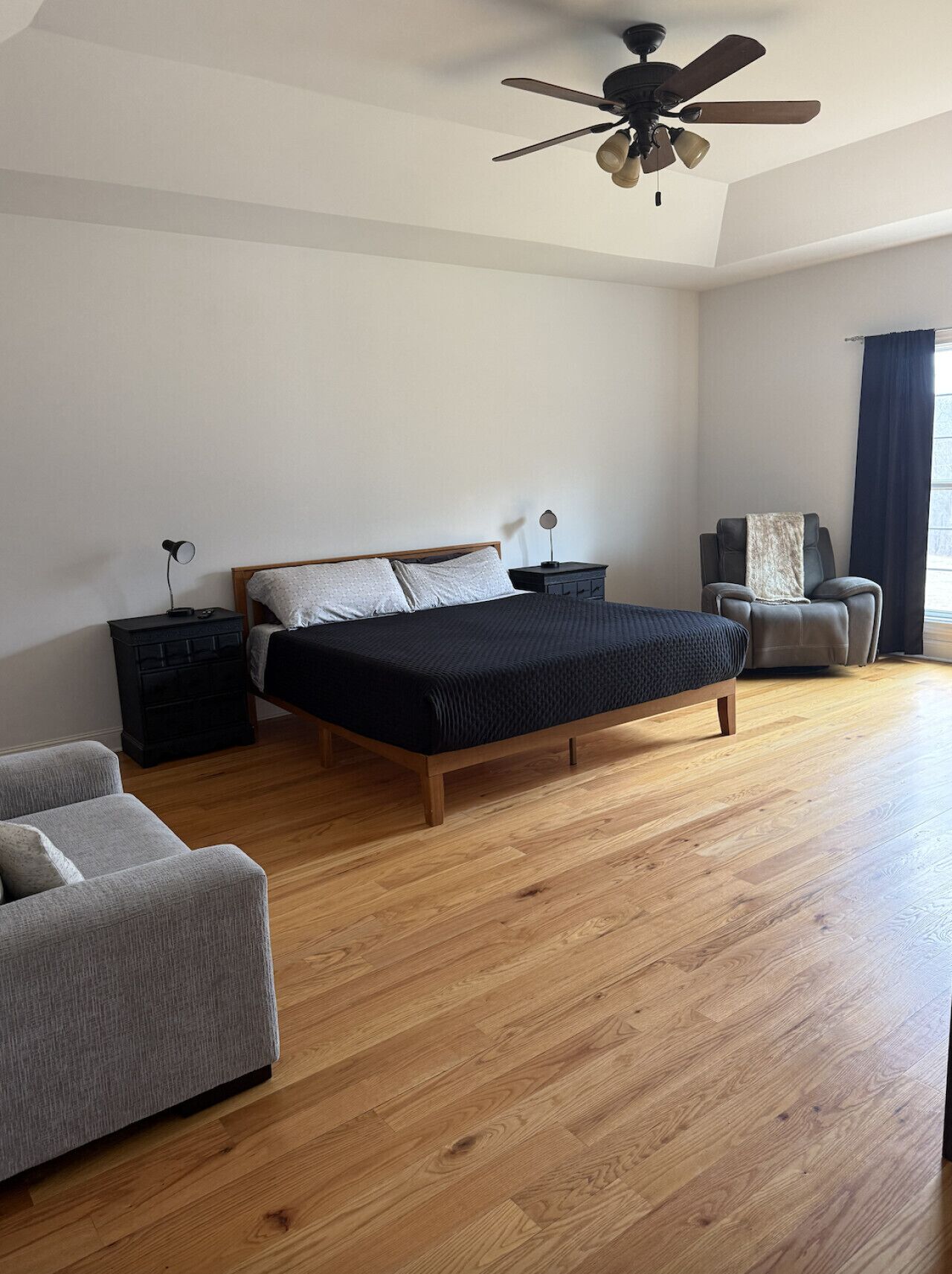 A bedroom with a bed, a chair, a desk, and a ceiling fan.