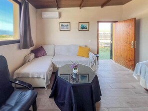 A room with a sofa, a table with a vase, a wooden door, and a view of the outdoors. - GuestReady - Pico del torreon (El Puerto de Santa María)