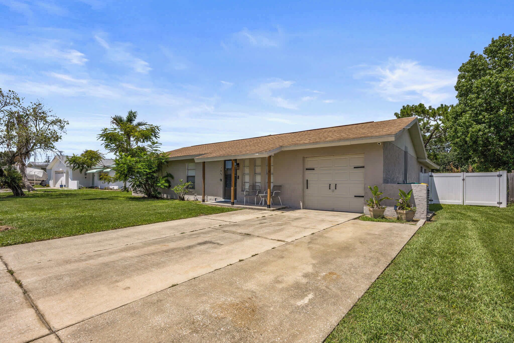 A single-story house with a garage, a front lawn, and a clear sky.