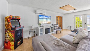 Uma sala de estar moderna com um console de jogos, uma TV de tela plana e uma lareira.