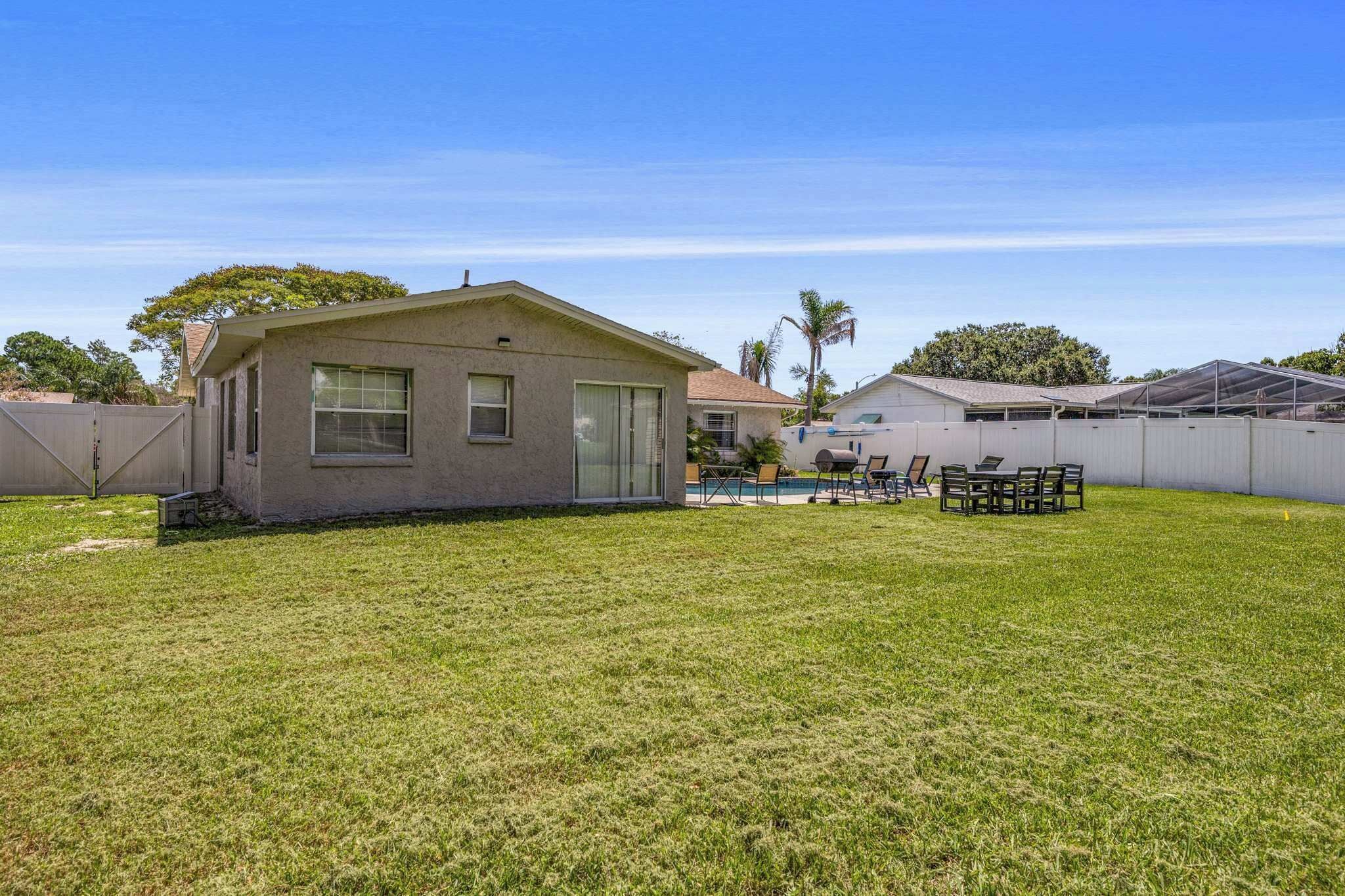 A residential property with a fenced backyard, a pool, and a covered patio area.