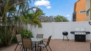 A patio with a table and chairs, a grill, and a white fence. - Group-Friendly 5BR/4.5BA with Private Yard (Indian Harbour Beach)