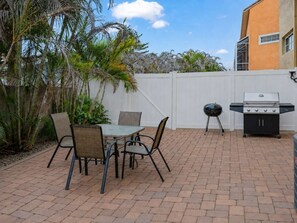 A patio with a table and chairs, a grill, and a white fence. - Group-Friendly 5BR/4.5BA with Private Yard (Indian Harbour Beach)
