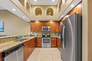 A kitchen with wooden cabinets, stainless steel appliances, and a granite countertop. - Group-Friendly 5BR/3.5BA with Private Yard (Indian Harbour Beach)