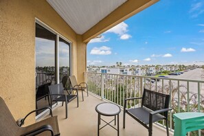 Ein Balkon mit Stühlen und Tisch, mit Blick auf einen Parkplatz und Gebäude.