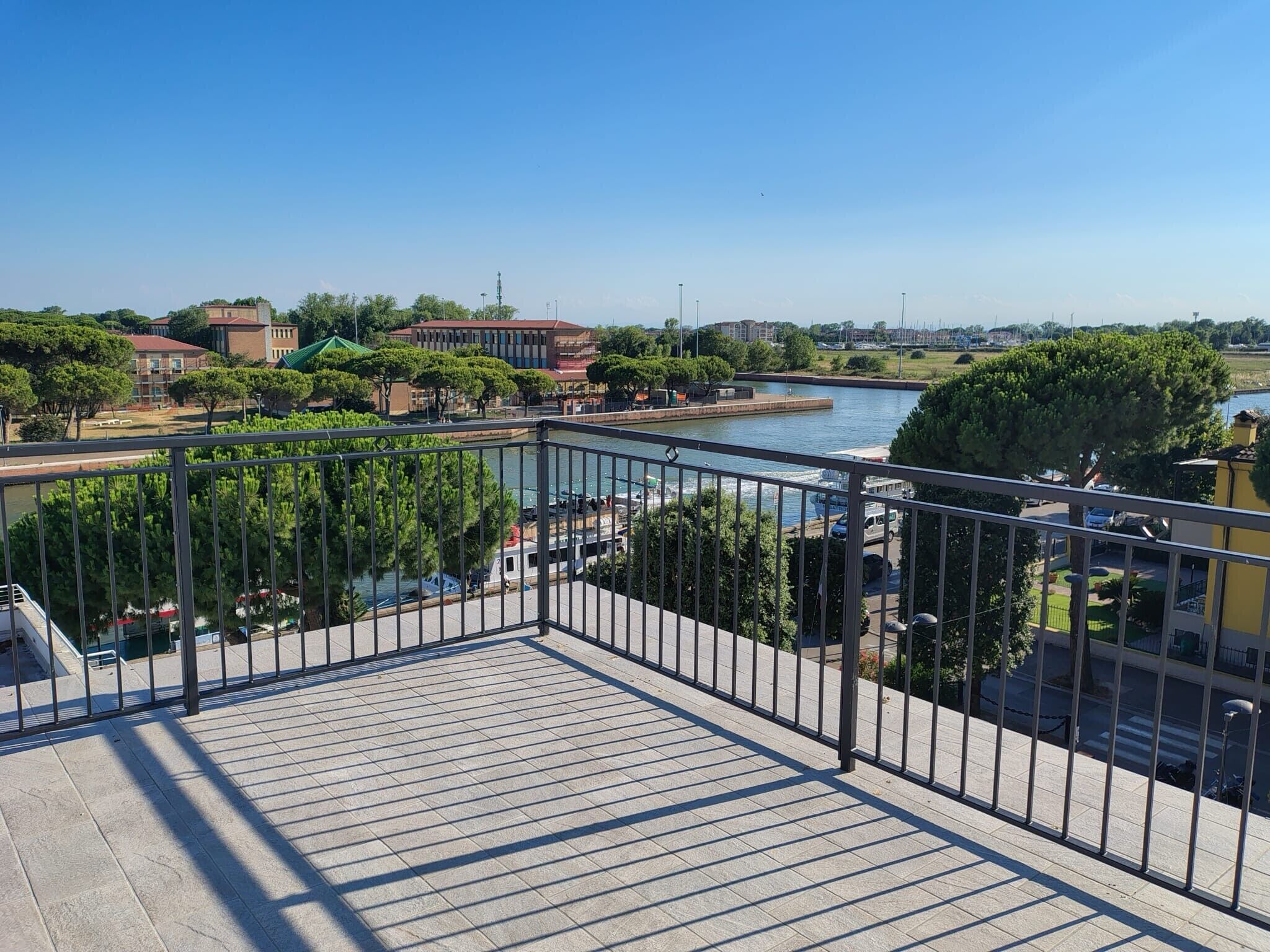 Uma varanda com vista para um rio, edifícios e vegetação.