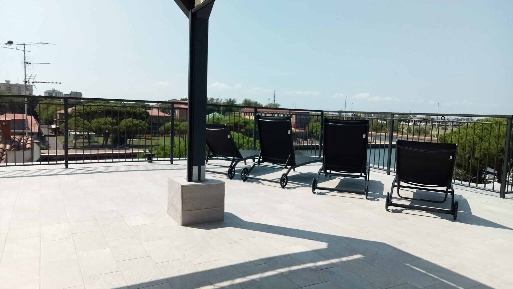 Une terrasse sur le toit avec trois chaises en métal noir et un bloc de béton.