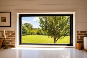 Una finestra amb vista a un paisatge verd i un arbre.