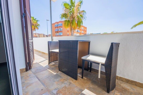 Un área de estar al aire libre con mobiliario de mimbre y piso de baldosas.