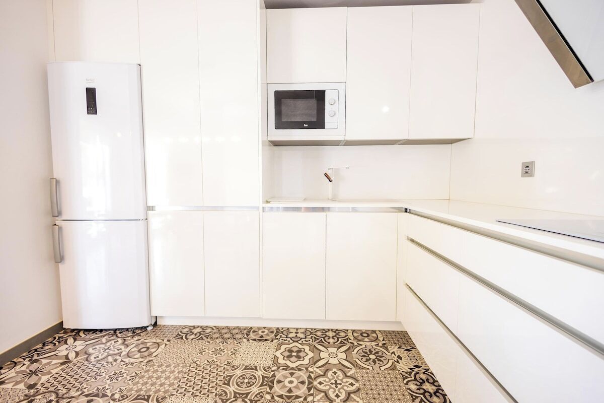 A kitchen with white cabinets, a microwave, and a refrigerator.