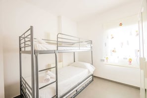 Un lit superposé avec des barreaux en métal, un matelas blanc et une fenêtre décorée de personnages de dessins animés.