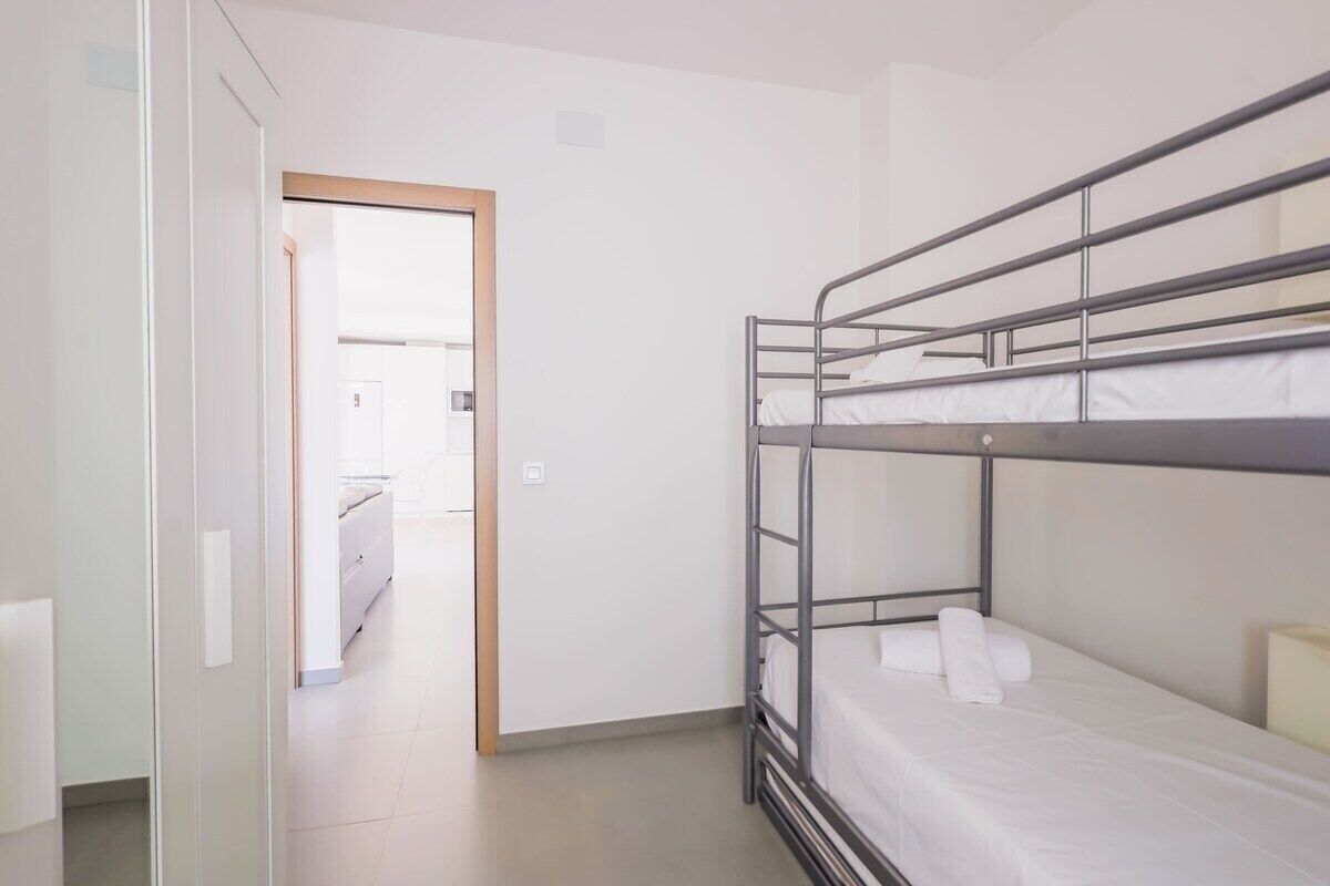 Een slaapkamer met stapelbed en een deur naar de badkamer.