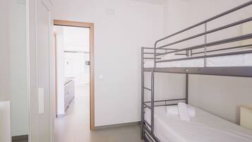 Een slaapkamer met stapelbed en een deur naar de badkamer.