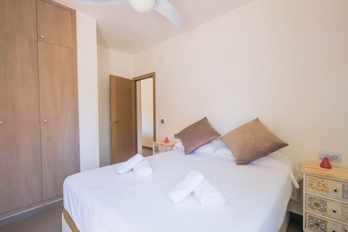 Een hotelkamer met een bed, een kledingkast, een nachtkastje en een spiegel.