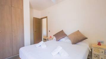 Een hotelkamer met een bed, een kledingkast, een nachtkastje en een spiegel.