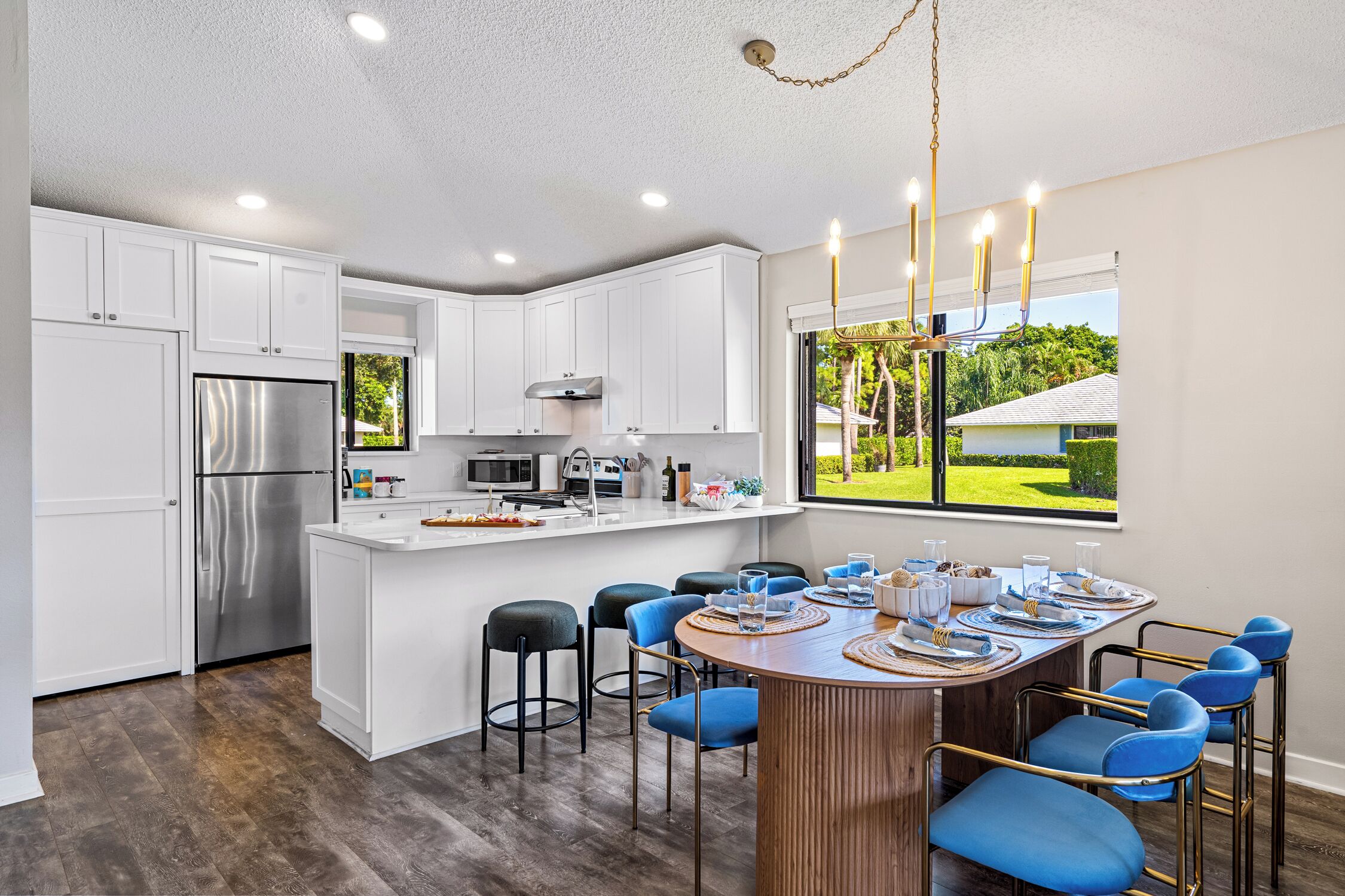 Una cocina moderna con armarios blancos, electrodomésticos de acero inoxidable y una isla central con taburetes de bar.