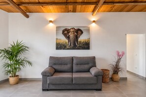 Un saló modern amb un sofà gris, un quadre gran d'un filó i dues plantes en testos.