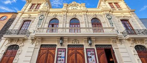 A historic building with ornate architecture, large wooden doors, and a balcony with wrought iron railings.
