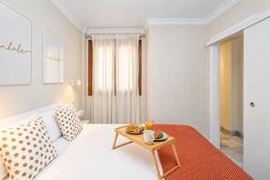 A hotel room with a bed, a breakfast tray, and a door leading to another room. - GuestReady - Urban Suite City Center (La Laguna)