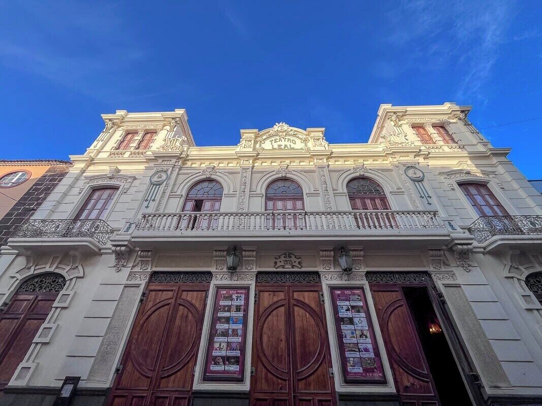 A historic building with ornate architecture, large wooden doors, and a balcony with railings.