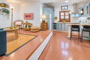 Eine moderne Küche mit einer zentralen Kochinsel, ein Essbereich mit einem blauen Sofa und einem Schild mit der Aufschrift 'GUEST READY'.