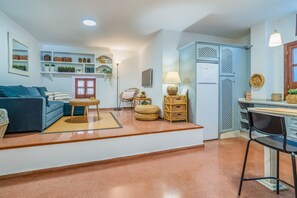 A living room with a sofa, a coffee table, and a dining area with a chair and table. - GuestReady - Plaza Corredera Modern Comfort (Córdoba)