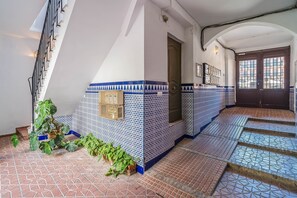 Eine Treppe mit blau-weißen gemusterten Fliesen, eine Tür mit einer verzierten Griff und eine Pflanze auf der linken Seite.