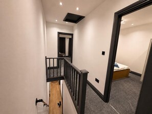 A hallway with a staircase leading to a bedroom. - Tranquil Haven in Hornchurch - 3 bed House (Hornchurch)