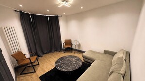 Ein modernes Wohnzimmer mit einer Couch, einem runden Couchtisch, einem Sessel und einer Heizung.