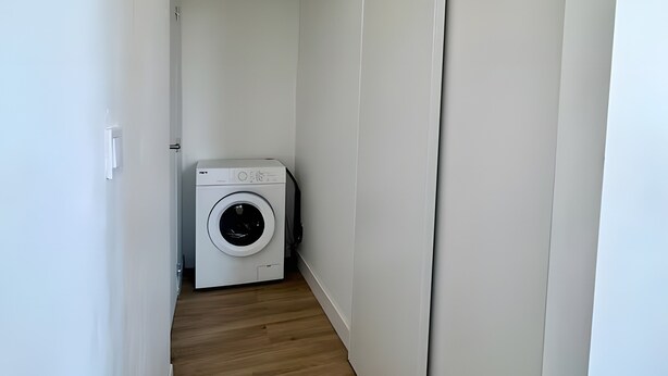 A narrow hallway with a washing machine and a sliding door closet. - Studio Apartment 'Diamant' with Balcony and Wi-Fi (Nice)