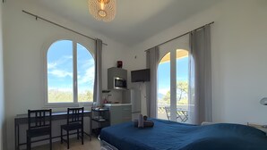 A bedroom with a bed, a desk with a chair, a television, and large windows. - Studio Apartment 'Diamant' with Balcony and Wi-Fi (Nice)