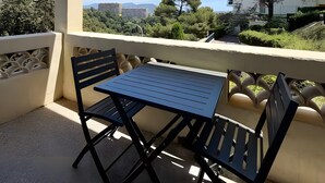 A balcony with a table and chairs, overlooking a cityscape with buildings and trees. - Studio Apartment 'Diamant' with Balcony and Wi-Fi (Nice)