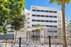 A modern building with a sign reading 'Vía Célere' and 'Port Avenue.' - GuestReady - Marbella with terrace and pool (Marbella)