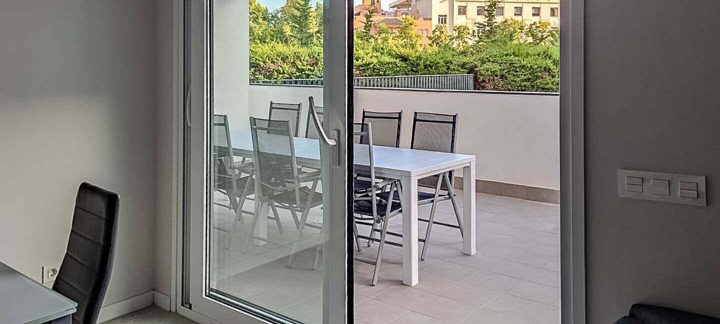 A room with a sliding glass door leading to an outdoor balcony with a table and chairs.