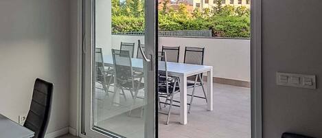 A room with a sliding glass door leading to an outdoor balcony with a table and chairs.