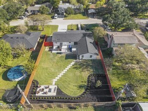 An aerial view of a residential property with a large lawn, a swimming pool, and a covered patio area. - Armistead Abode - Walk to TAMU & Kyle Field! (College Station)