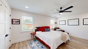 A bedroom with a bed, a ceiling fan, a window with blinds, and framed artwork on the wall. - Armistead Abode - Walk to TAMU & Kyle Field! (College Station)