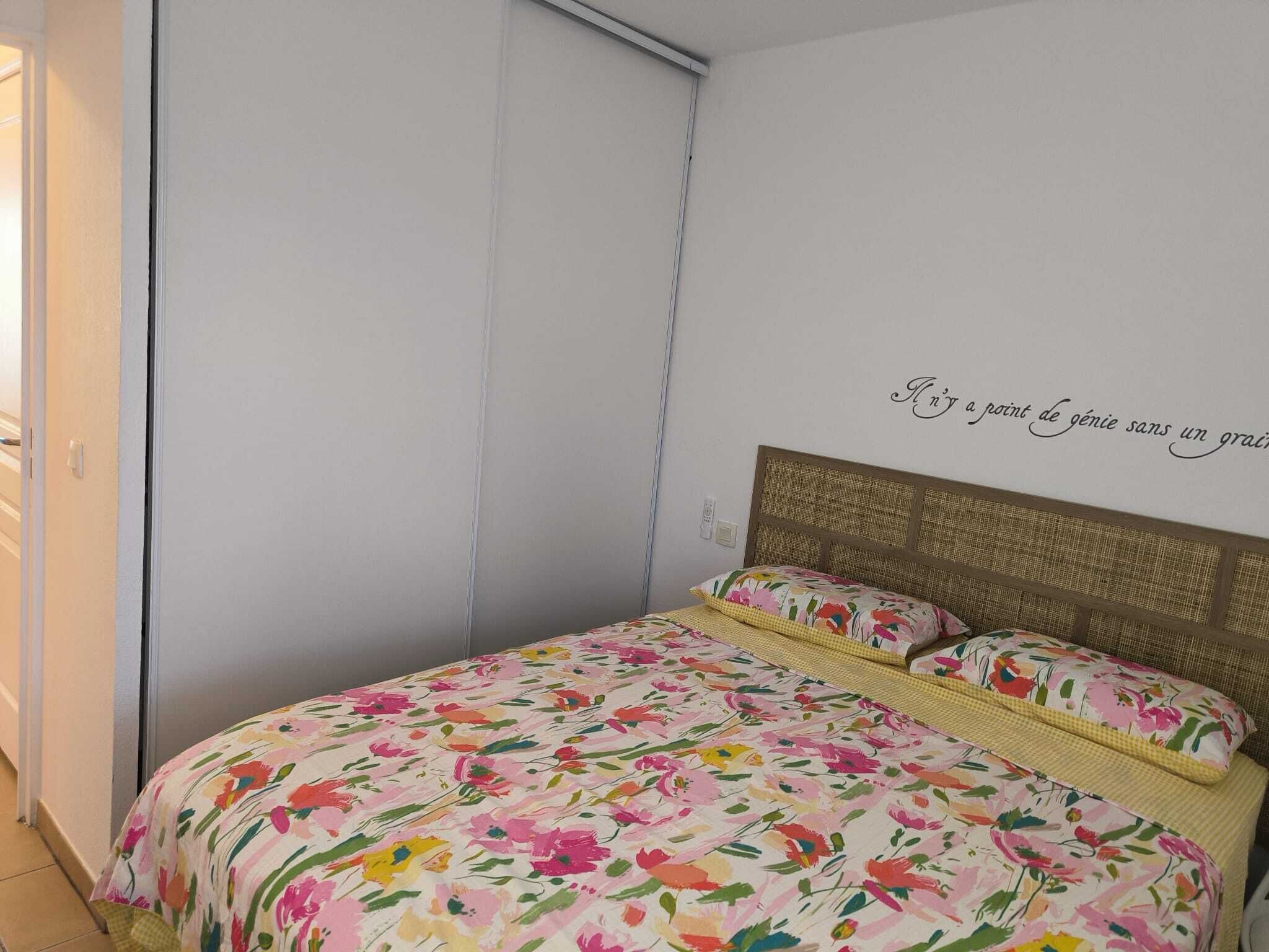 Een slaapkamer met een bed, hoofdeinde en een muur met een citaat.