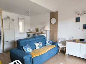 Un espace de vie compact comprenant un canapé, un coin repas et une kitchenette.
