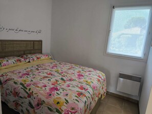A bedroom with a bed, a window, and a wall quote.